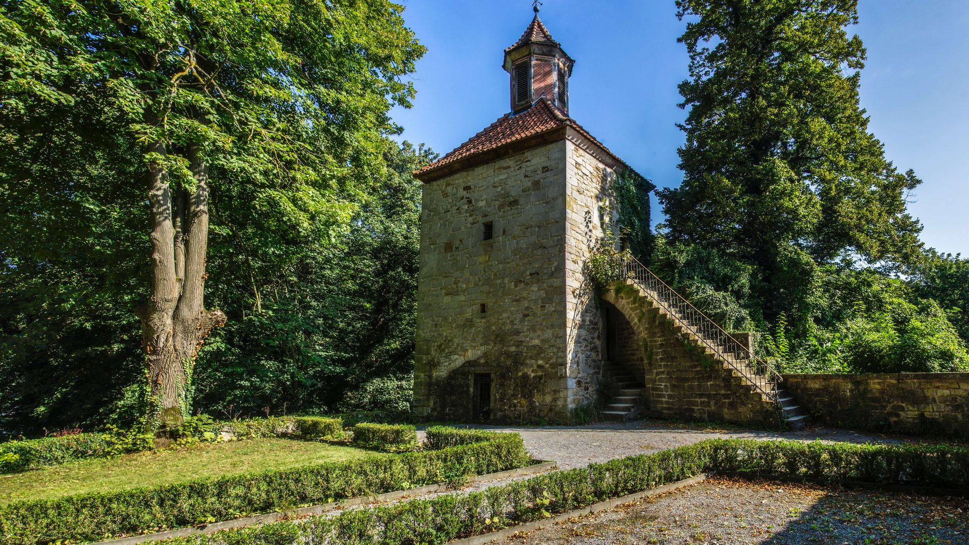 Schaumburg - Glockenturm mit Beet und Bäumen, Rinteln