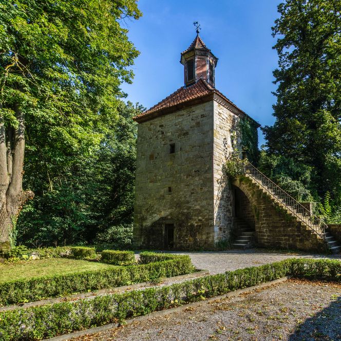 Schaumburg - Glockenturm mit Beet und Bäumen, Rinteln